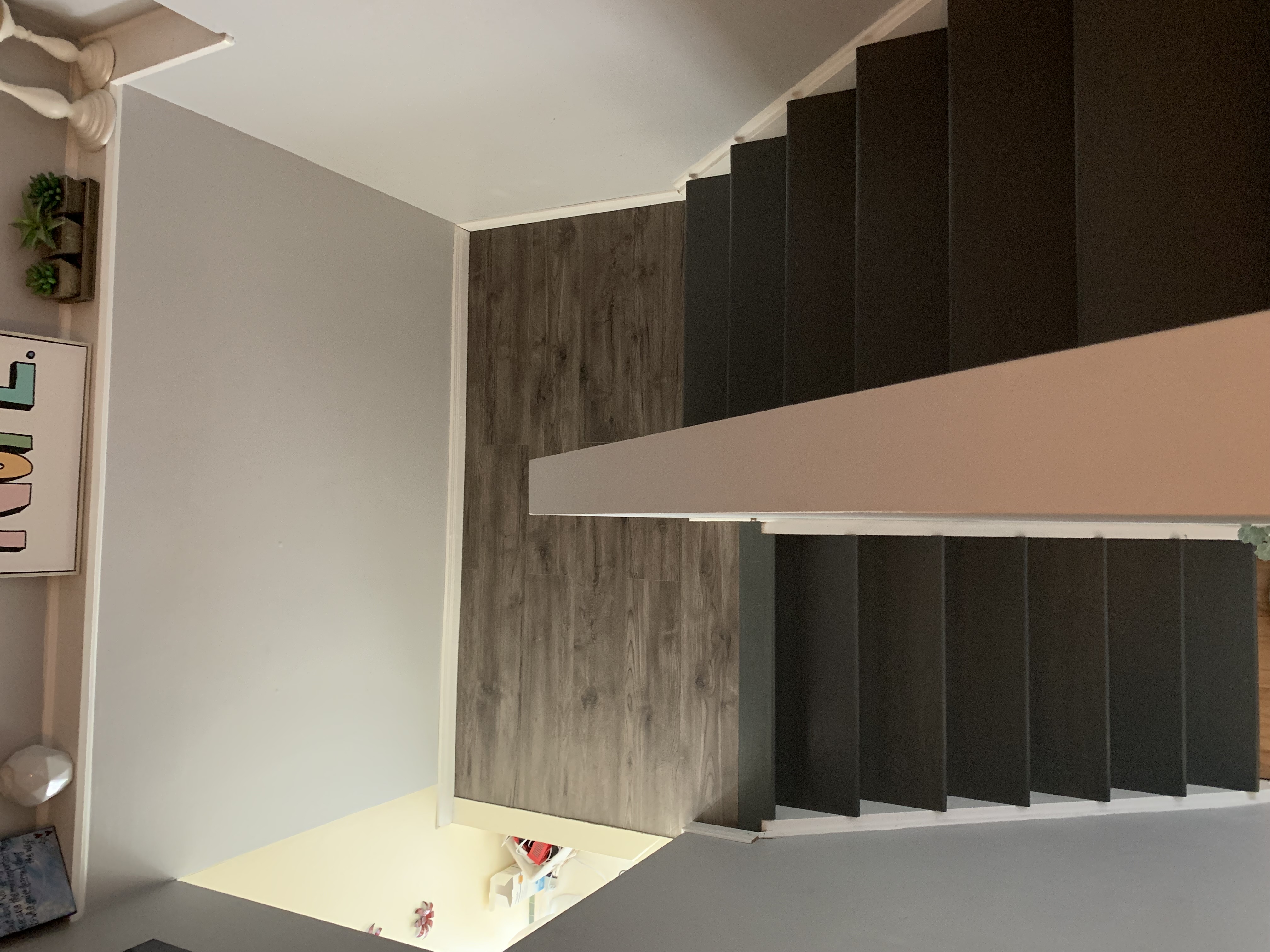 LVP flooring installation on a upper landing, with painted stair stringers and clean trim transitions.