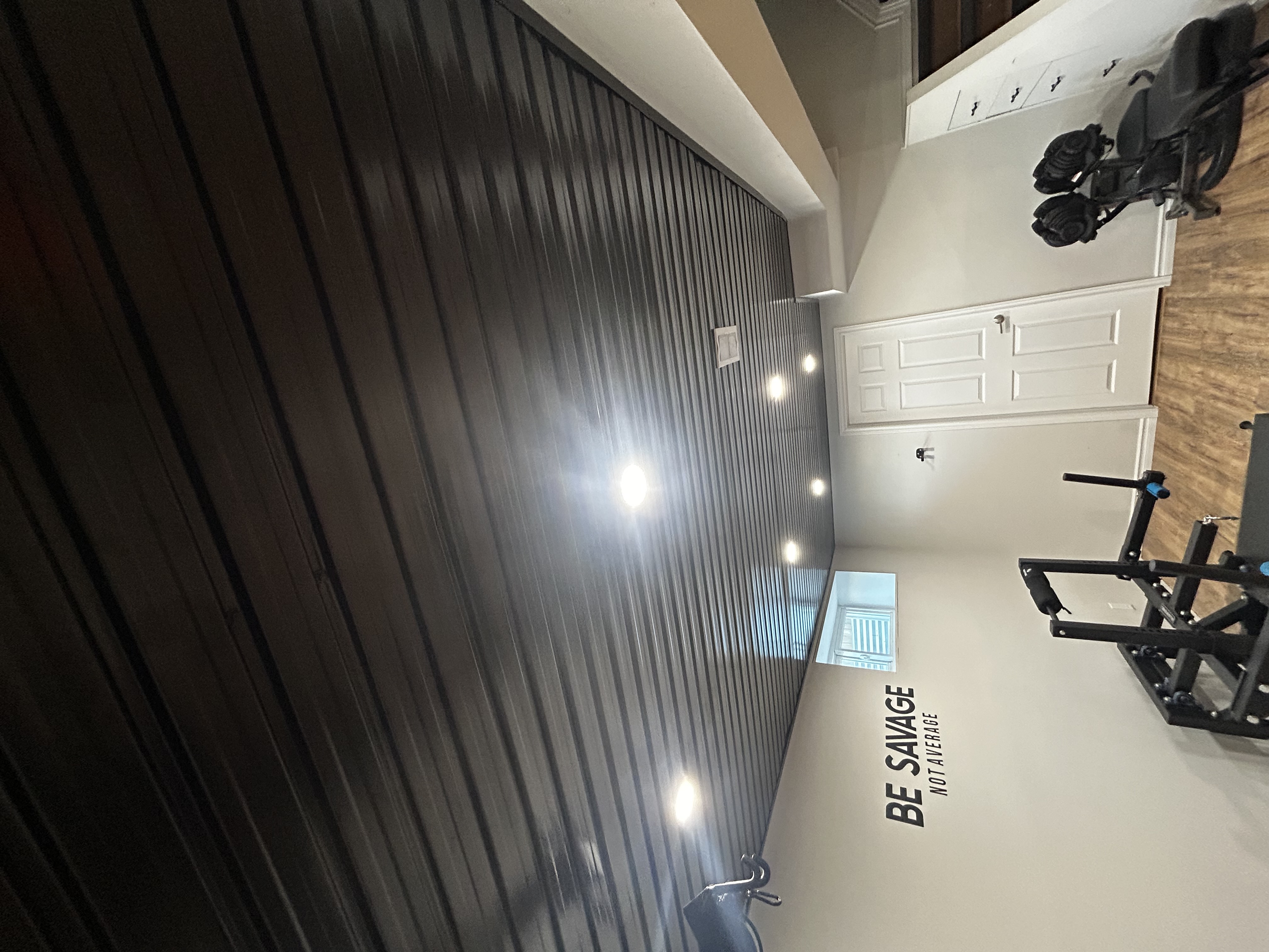 Tongue-and-groove ceiling plank install in a basement gym space, finished with pot light cutouts and painted trim.